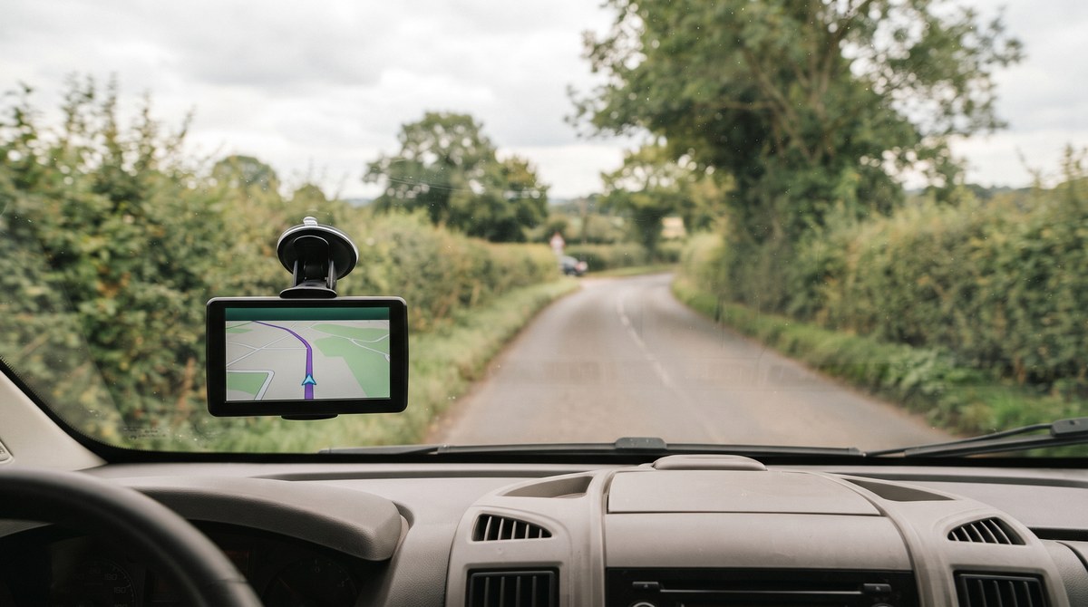 Navigationsgeraet an der Windschutzscheibe eines Wohnmobils mit Blick auf eine Landstrasse